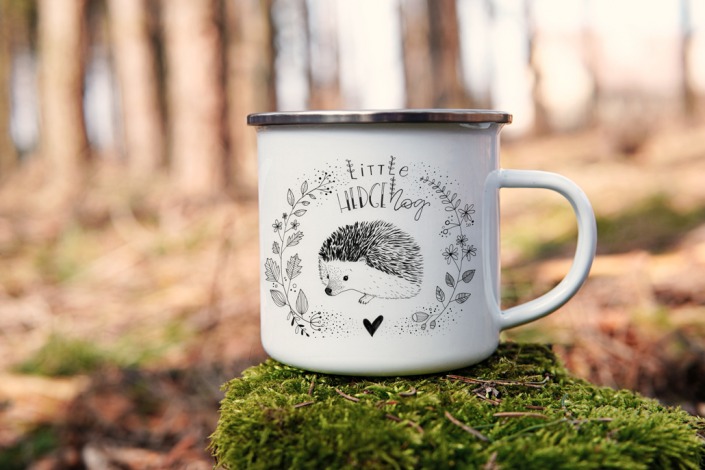 Enamel mug in the woods showing a little hedgehog