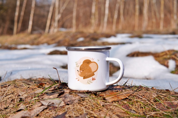 A children's mug with a bear placed on some leaves